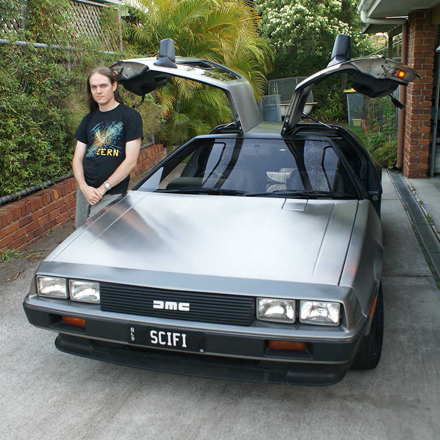 Mike Ando aka riumplus aka RIUM+ standing beside his DeLorean